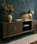 Wooden sideboard with brushed nickel cabinet handles, featuring books and a lamp, in a stylish living room setting.