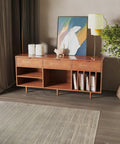 Modern living room with wooden sideboard featuring abstract artwork and potted plant, complemented by a rug and elegant decor items.