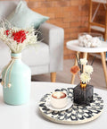 12 inch mother of pearl lazy susan turntable with floral pattern on a table holding a coffee cup and decorative vases.