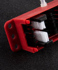 Close-up of red Universal Motorcycle Chain Cleaning Kit With Brush Cleaner Lube Device showing black and white bristles on black background.