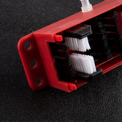 Close-up of red Universal Motorcycle Chain Cleaning Kit With Brush Cleaner Lube Device showing black and white bristles on black background.