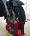 Deluxe One Size Fits All Orange And Black Motorcycle Wheel Chock With Quick Disconnect Mounting Plate And Built In Front Tire Tie Down Solid Powder Coated Steel Construction Self Locking Deluxe Wheel Chock For Easy Trailering From Lock N Load