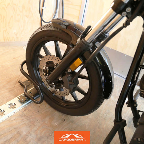 Heavy Duty Motorcycle Wheel Chock For Trailers That Connects To X Track And E Track Systems And Stabilizes Front Or Rear Wheel, Fits Up To 7 Inch Wide Tires, Ideal For Secure Hauling On The Move CargoSmart shown securing a motorcycle wheel in a trailer.