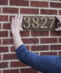 Man installing house number plaque using Heavy Duty Clear Double Sided Mounting Tape For All Weather Indoor And Outdoor Use 1 Inch By 60 Inch Roll Transparent Adhesive That Holds Up To 30 Pounds Per Roll Ideal For Metal Glass Wood Concrete Brick Tile Ceramics And More.