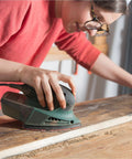 Person using a Ryobi sander with Mouse Sanding Pads Assortment for Ryobi Sander 70 Pc 6 Hole with 40 to 320 Grit on wood surface