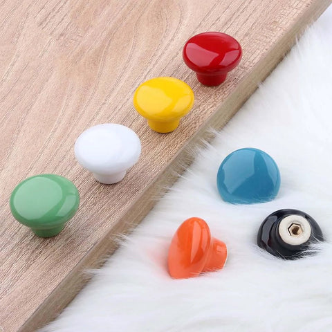 Assorted round ceramic knobs with red, yellow, white, green, turquoise, orange, and black colors for cabinets and drawers.