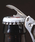 Framework Mini 11 In 1 Multitool Open Frame with bottle opener in use on a bottle cap, showcasing multifunctional capabilities.