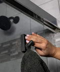 Hand applying black hook with Nano Grab Technology Double Sided Gel Tape For Clear Mounts And Quick Fixes on shower door
