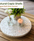12 inch white capiz lazy susan turntable centerpiece with flowers and candle on a wooden table
