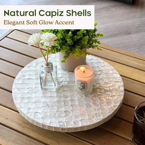 12 inch white capiz lazy susan turntable centerpiece with flowers and candle on a wooden table