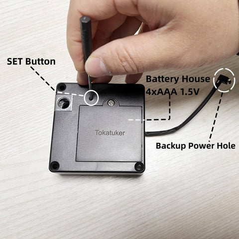Backside view of a discreet USB powered cabinet lock with NFC and RFID access, showing set button and battery compartment on wood surface.