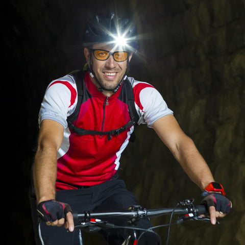 Cyclist wearing Night Vision Driving Glasses With Anti Glare Yellow Polarized Lenses and a headlamp in a tunnel.