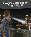 Man using As Seen On TV Mega Bright Rechargeable Spotlight With 10 Modes And Turbo Boost Up To 100 Percent overlooking cityscape at night.