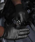 Person wearing Nitrile Gloves 10 Mil Thick With Diamond Texture Puncture Resistant Powder Free while using a wrench in automotive setting