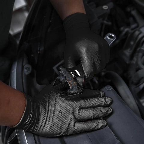 Person wearing Nitrile Gloves 10 Mil Thick With Diamond Texture Puncture Resistant Powder Free while using a wrench in automotive setting