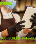 Person wearing Nitrile Disposable Gloves 4 Mil Latex Free Powder Free Black XL 100 Count using a tablet in a cafe setting.