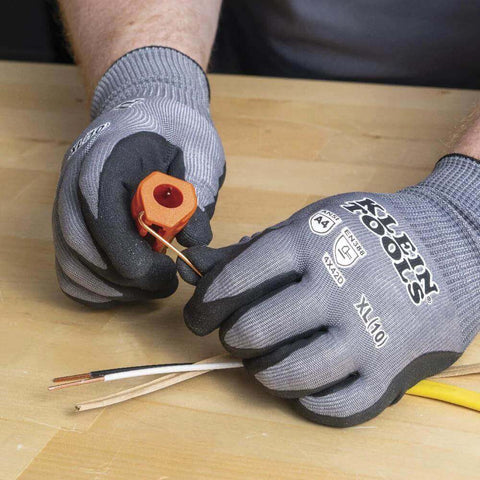 Person using Five In One Cable Stripping Tool for 12 to 14 AWG NM cable to strip insulation on wooden table.