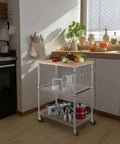 Heavy Duty 3 Tier Rolling Kitchen Cart Workhorse With Oak Wood Top And Drawer Slider Chrome Finish Four Wheels Hooks For Utensils 300 Lb Total Capacity Multi Function Kitchen Island Cart For Cooks And Caterers Finnhomy shown in a kitchen setting with utensils.