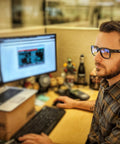 Man at desk wearing ANSI Z87.1 Safety Glasses With Anti Fog UV Protection Clear Lens Side Shields, working on computer