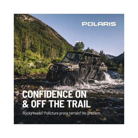 Off-road vehicle driving through water on rocky terrain under clear sky