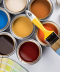 Open paint cans with various colors and a paintbrush on top, including blue, brown, yellow, and red paint.