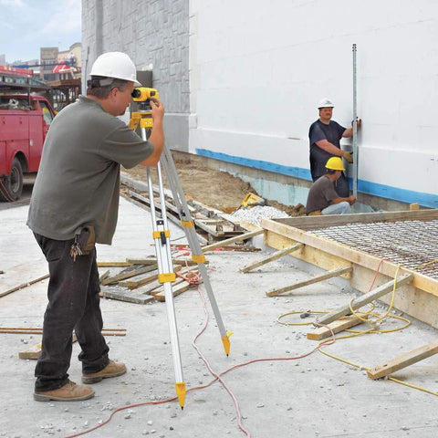 Worker using Dewalt 26x Automatic Optical Level Kit With Tripod And Rod Delivers Precise Elevations And Fast Readings For Surveying, Grading, And Leveling On Construction Sites, With 26x Magnification, 1/32 In Per 100 Ft Accuracy, And A Durable Carrying Case at a construction site.