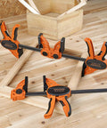 Two Pack Six Inch One Hand Clamp And Spreader Set With 300 Lb Clamping Force on a wooden frame