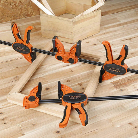 Two Pack Six Inch One Hand Clamp And Spreader Set With 300 Lb Clamping Force on a wooden frame