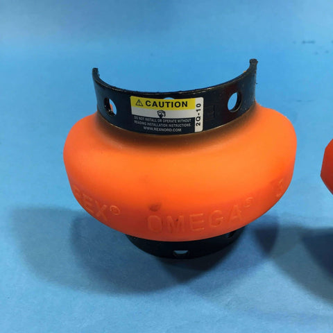 Orange mechanical coupling element with caution label, used in industrial shaft applications, on blue background.