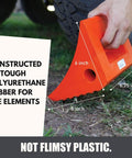 Heavy Duty Wheel Chocks Two Pack That Prevents Movement On Slopes For Boat Trailers RVs Trucks And Campers All Weather Non Slip Solid Rubber With Orange Color By SecurityMan. An orange wheel chock with handle shown in use on grass.