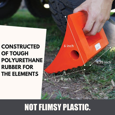 Heavy Duty Wheel Chocks Two Pack That Prevents Movement On Slopes For Boat Trailers RVs Trucks And Campers All Weather Non Slip Solid Rubber With Orange Color By SecurityMan. An orange wheel chock with handle shown in use on grass.