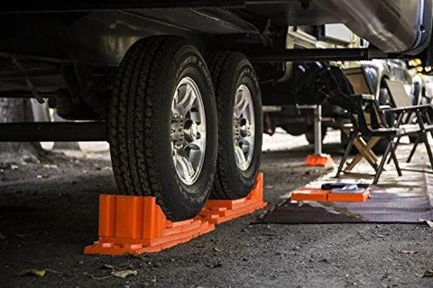 Interlocking RV Leveling Blocks 10 Pack With Nylon Storage Bag For Trailer Motorhome And Vanlife Up To 40,000 Lbs Capacity Orange in use under RV tires, stabilizing on uneven terrain.