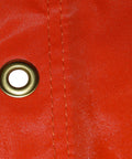 Close-up of orange nylon material with metal eyelet from USA Made 18 Inch By 60 Inch Orange And White Nylon Windsock Kit With Heavy Duty Ball Bearing Frame For Rugged Airport Signaling And Easy Mounting At Airports Farms And Industrial Sites Airport Windsock Corporation.