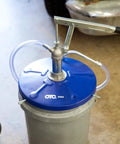 OTC 2352 Lever Action Bucket Pump on a 5-gallon pail, featuring a lever handle, blue drum cover, and discharge hose