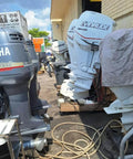 Various marine outboard motors including covered units and cables in an outdoor storage area.
