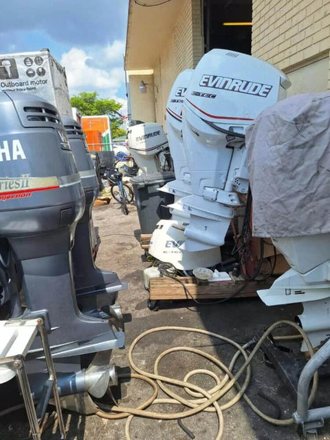 Various marine outboard motors including covered units and cables in an outdoor storage area.