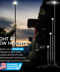 Person using Outdoor LED Tripod Lantern With 1200 Lumens Adjustable 9 Foot Height Grab And Go Camping Light For Hiking Backyard And Emergencies Long Battery Life Rugged Aluminum Build Easy Setup near a car.