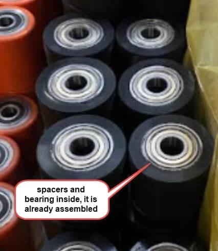 Pallet Jack Load Wheel with poly steel hub, 3 x 2.5 inch size, pre assembled, visible spacers and bearings, stacked in storage.