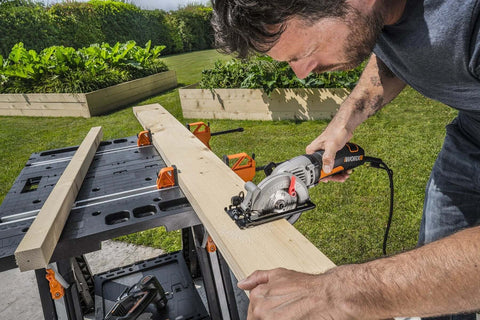 Man using Pegasus 2 In 1 Folding Work Table And Sawhorse Portable Workbench With Clamps WX051 to cut wood plank outdoors
