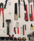 Assorted hand tools including wrenches, pliers, and hammers organized on a pegboard in a garage or workshop setting.