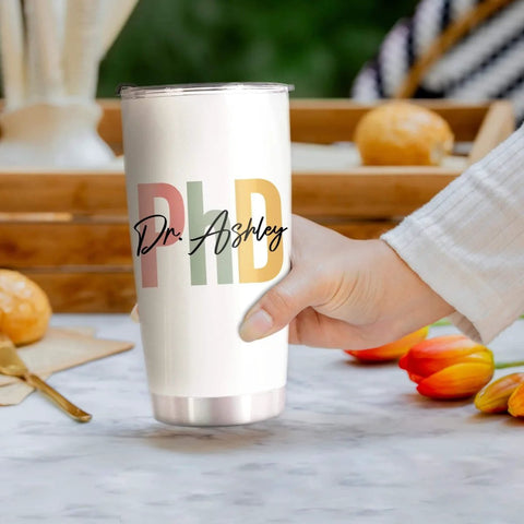 Hand holding Personalized 20 Oz PhD Tumbler For Women And Men, Doctor Of Philosophy Gift, Custom Doctoral Degree Cup with Nutrition Facts.
