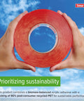 Hands holding a roll of red double-sided tape with a blue sky background, emphasizing sustainable materials and branding.