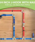 Plumbing installation with red and blue 3/4 inch PEX pipes using J-hooks and nails on wooden board.