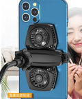 Smartphone with cooling fans attached to the back, smiling person in the background, visible mount adapter.