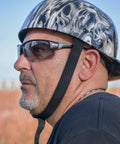 Man wearing Hercules 7 Photochromic Safety Sunglasses With Auto Darkening Lenses ANSI Z87.1 and a skull patterned helmet outdoors