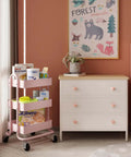 Pink 3 Tier Utility Rolling Cart On Wheels For Kitchen Office Home And Garden Elitehouse Metal Storage Cart With Locking Wheels Durable Mobile Organizer 13.4 By 18.1 By 31 Inches placed beside a white dresser in a children's room.