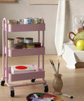 Pink 3 Tier Utility Rolling Cart On Wheels For Kitchen Office Home And Garden Elitehouse Metal Storage Cart With Locking Wheels Durable Mobile Organizer 13.4 By 18.1 By 31 Inches in a room setting with art supplies.