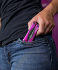 Person placing Pink 14-In-1 Aluminum Multi-Tool With Stainless Steel Tools into jeans pocket, illustrating compact size for everyday carry.