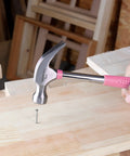 8 oz claw hammer with a shock-absorbing non-slip pink grip used for driving a nail into wood with durable steel head and claw