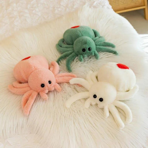 Trio of colorful plush spider toys with red spots on a soft surface, showcasing playful design and cuddly texture.
